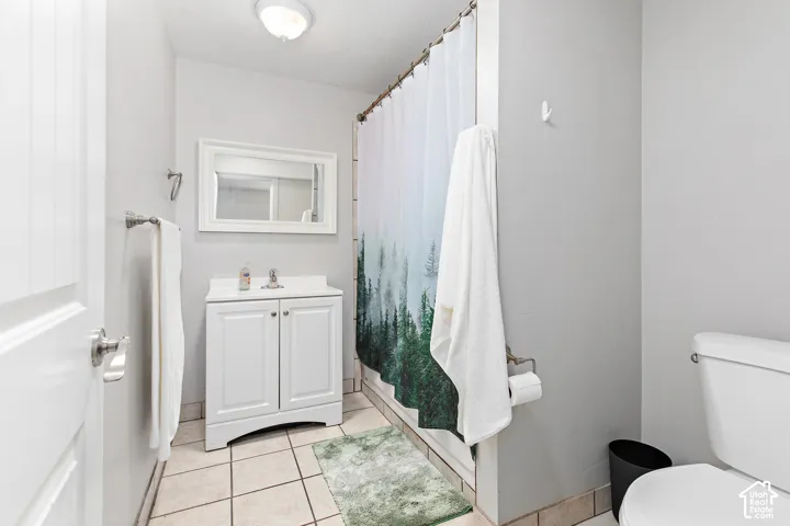 White vanity with under-sink storage, framed mirror, and tile flooring