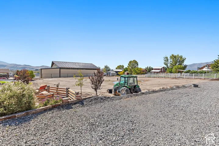 Expansive gravel surface, white fencing, and a large metal-clad barn structure