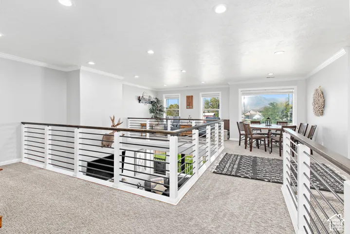 Carpeted loft space with recessed lighting, crown molding, and modern horizontal railing