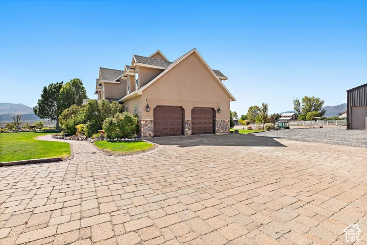Paver driveway with a curved paver pathway, two-car garage, and stone accent facade