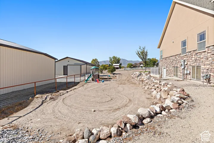 Exterior featuring a rock retaining wall, stone accent siding, and multiple outbuildings