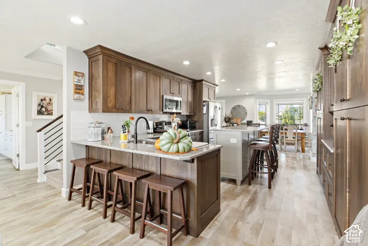 Kitchen featuring wood-finish flooring, recessed lighting, wood cabinetry, and a central island with bar seating
