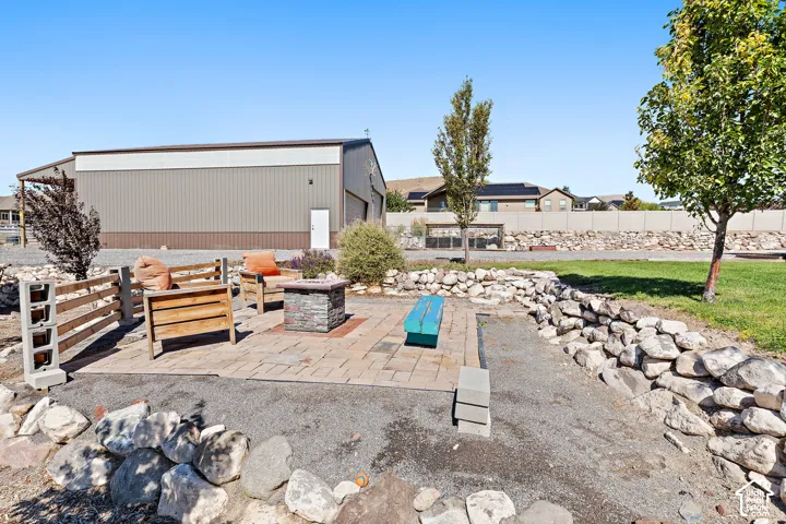 Expansive outdoor patio with paver flooring and a stone-clad fire pit