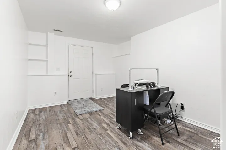 Wood-finish flooring, white paneled walls, built-in shelving, white door with textured glass detail, and overhead dome lighting