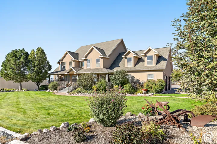Stucco exterior residence featuring a covered front porch, dormer windows, and a multi-level roofline