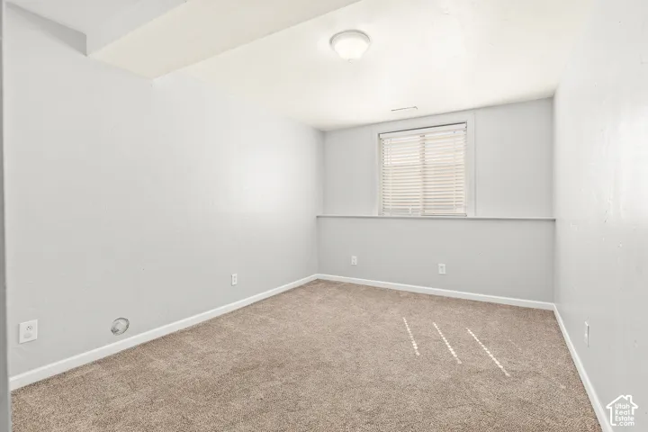 Carpeted flooring, recessed window with blinds, ceiling-mounted light fixture, and light-toned wall paint