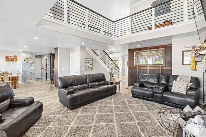 Two-story living area featuring a vaulted ceiling, wood-finish flooring, and a second-story interior balcony with metal railings