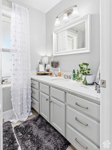 Recessed sink with a light-toned countertop, extensive cabinetry with brushed nickel hardware, and a framed mirror