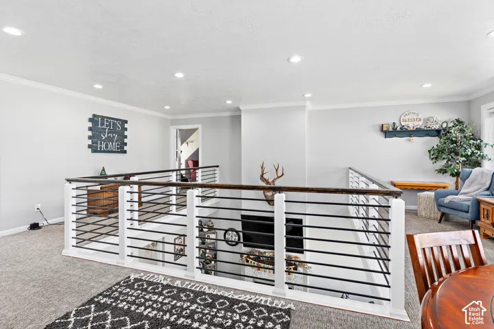 Carpeted upper level with recessed lighting, crown molding, and a contemporary horizontal bar railing with a wood-finish top rail