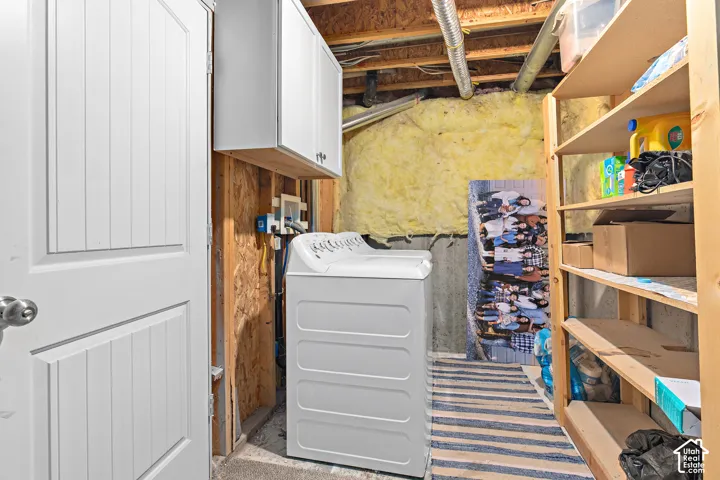 Built-in wooden shelving, overhead cabinetry, and a top-loading washing machine