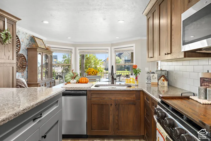 Kitchen featuring wood cabinetry, stainless steel appliances, white subway tile backsplash, and light-toned countertops