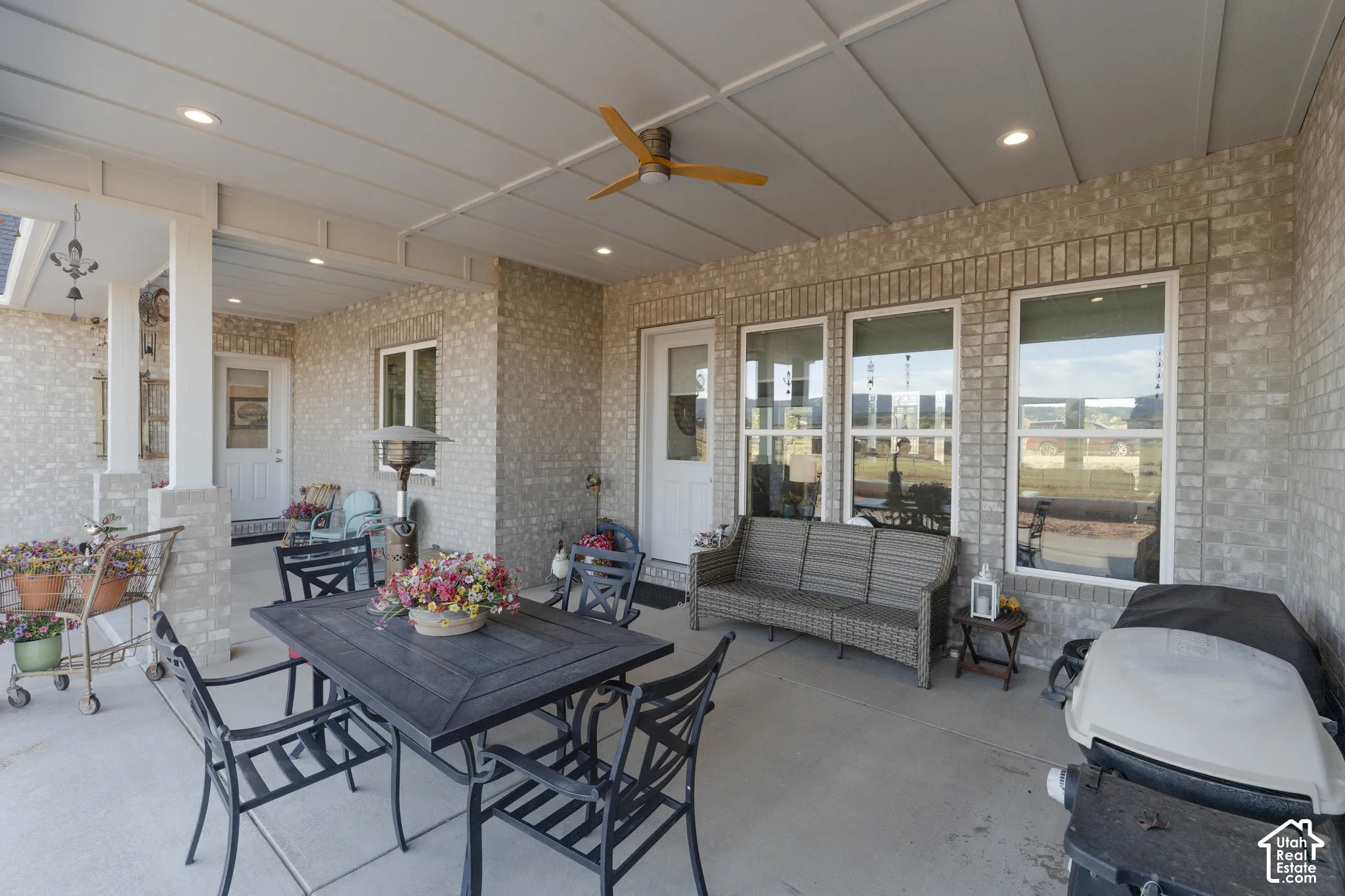 Covered patio featuring brick exterior walls, recessed lighting, ceiling fan, and multiple exterior doors