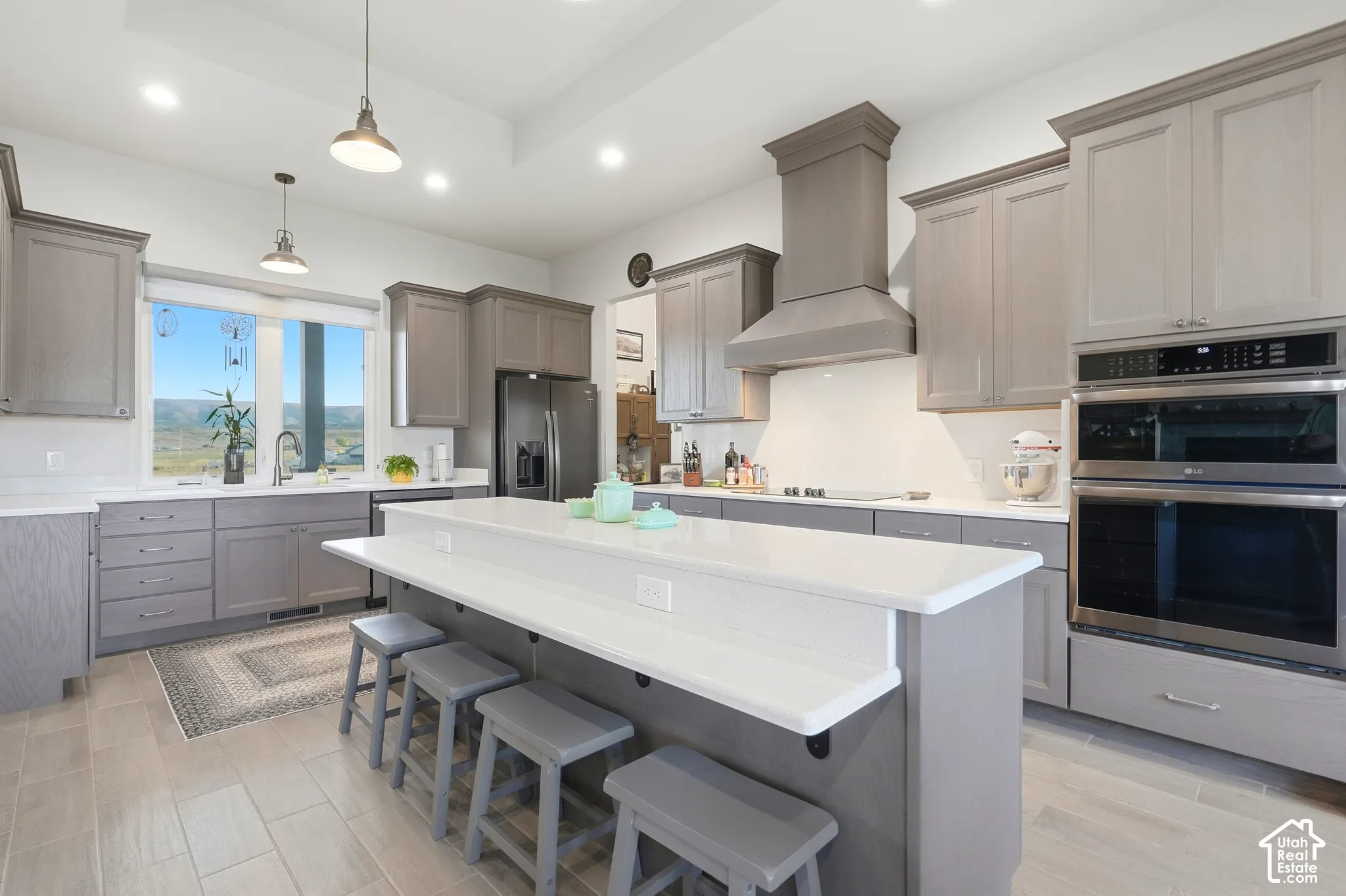 Gourmet kitchen featuring a large central island, light-toned cabinetry, stainless steel appliances, and tile flooring