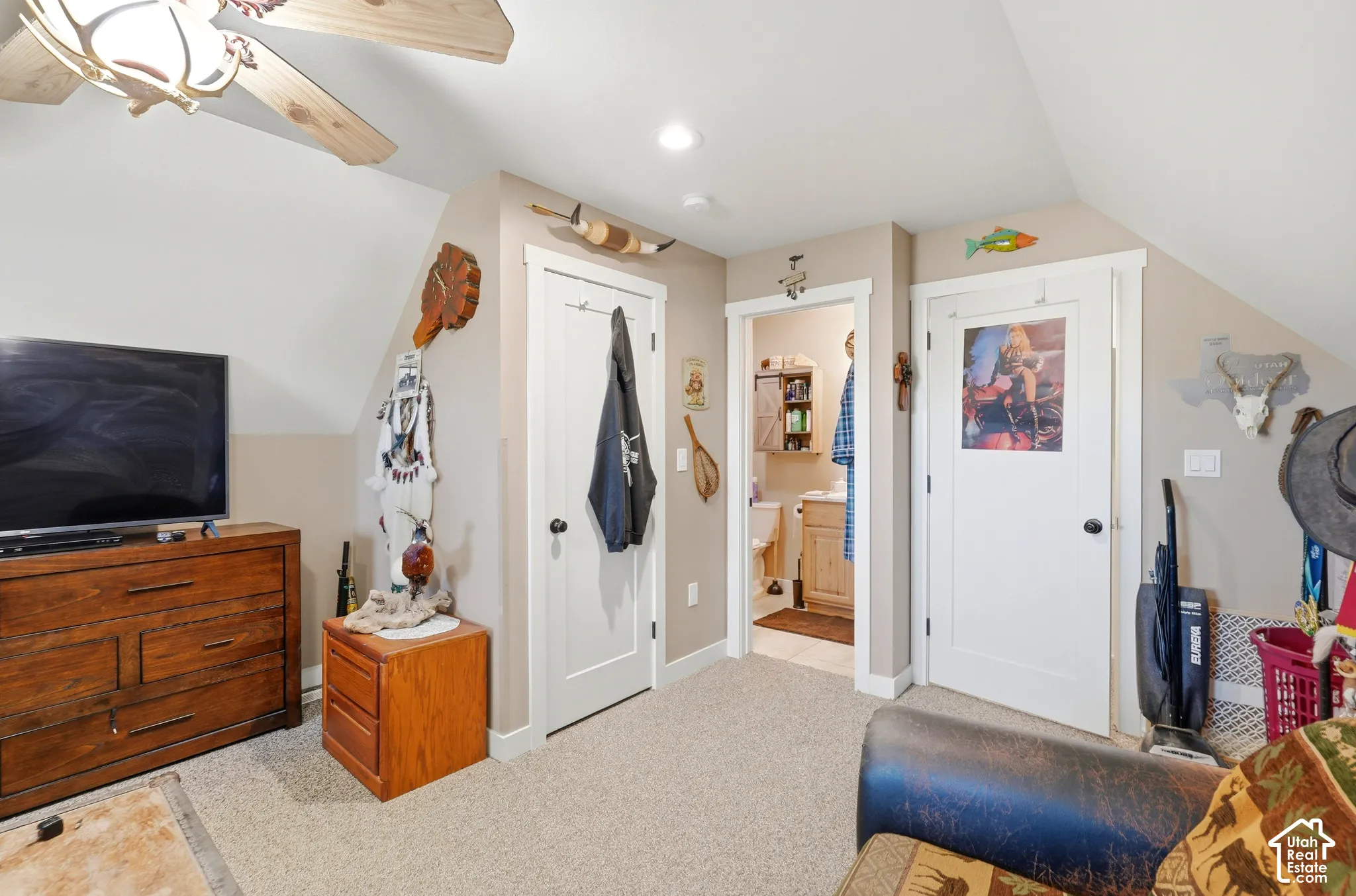 Carpeted flooring, vaulted ceiling, recessed lighting, and a visible bathroom entrance with a wood-finish vanity