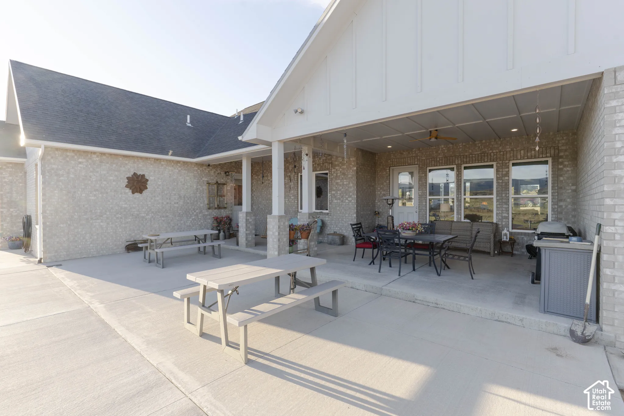 Expansive concrete patio featuring a covered outdoor living area with a ceiling fan, recessed lighting, and multiple large windows