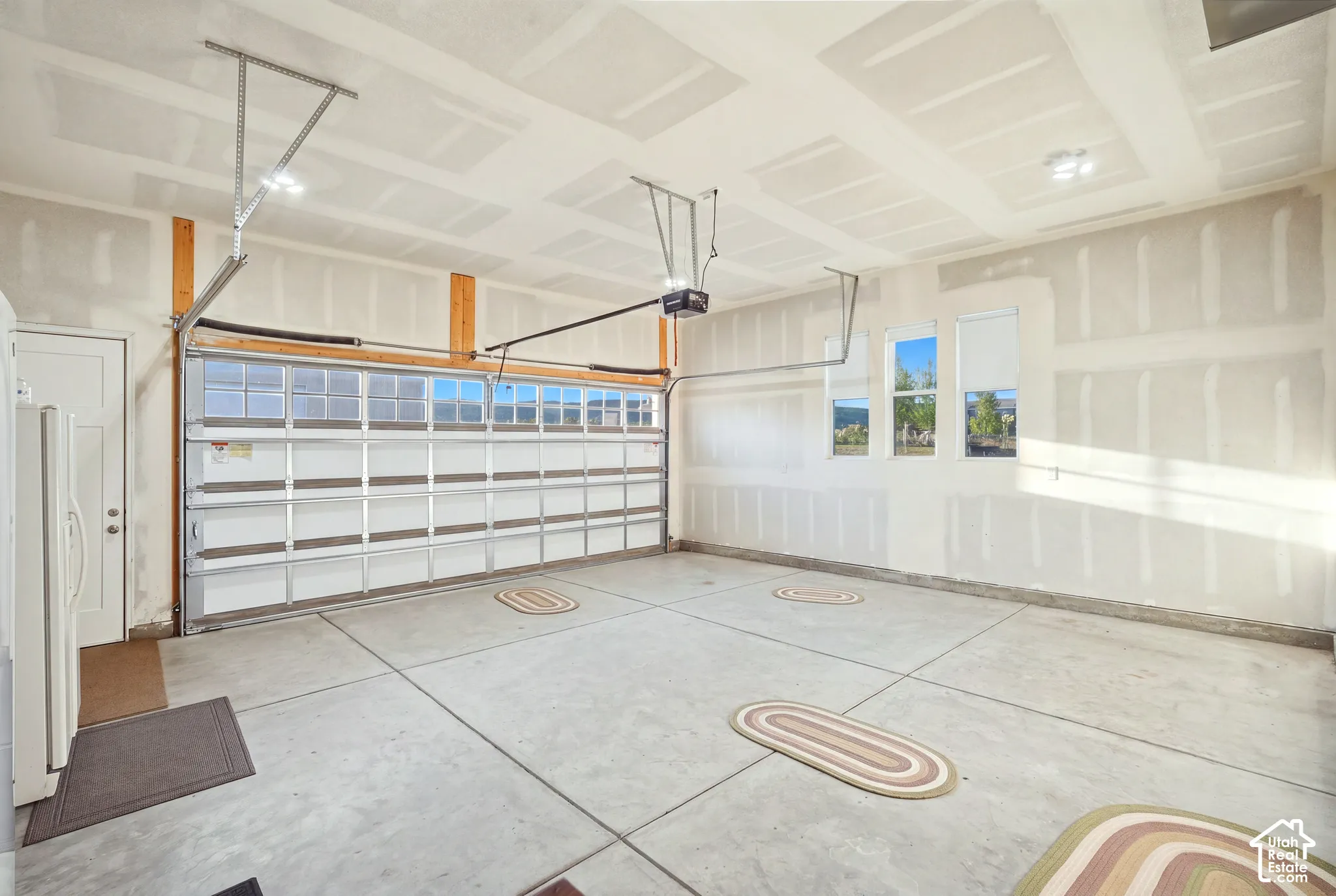 Spacious garage featuring a paneled overhead door with upper window inserts, multiple windows for natural light, and an interior access door