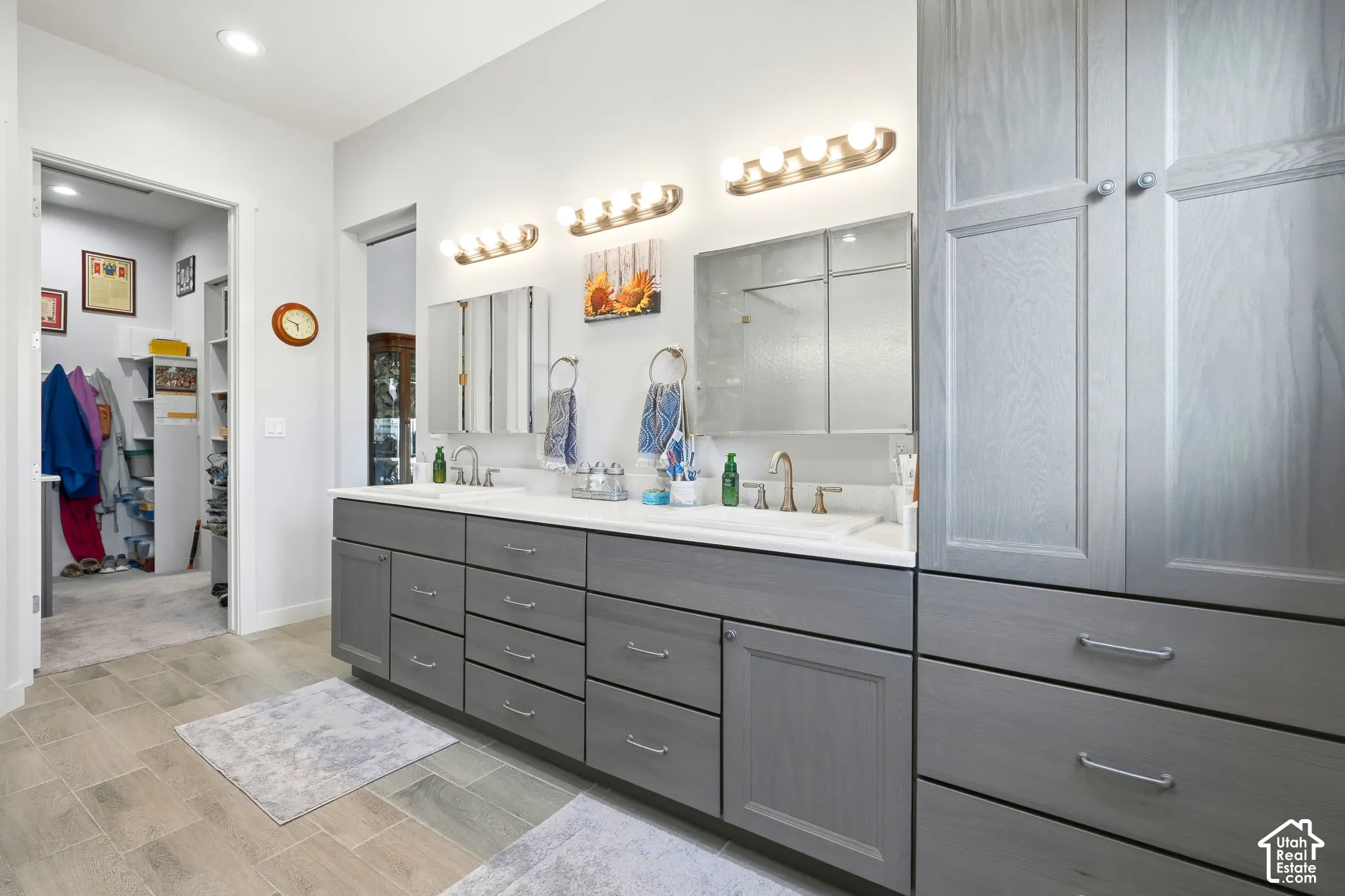 Dual sink vanity with grey cabinetry, white countertops, and a built-in linen cabinet