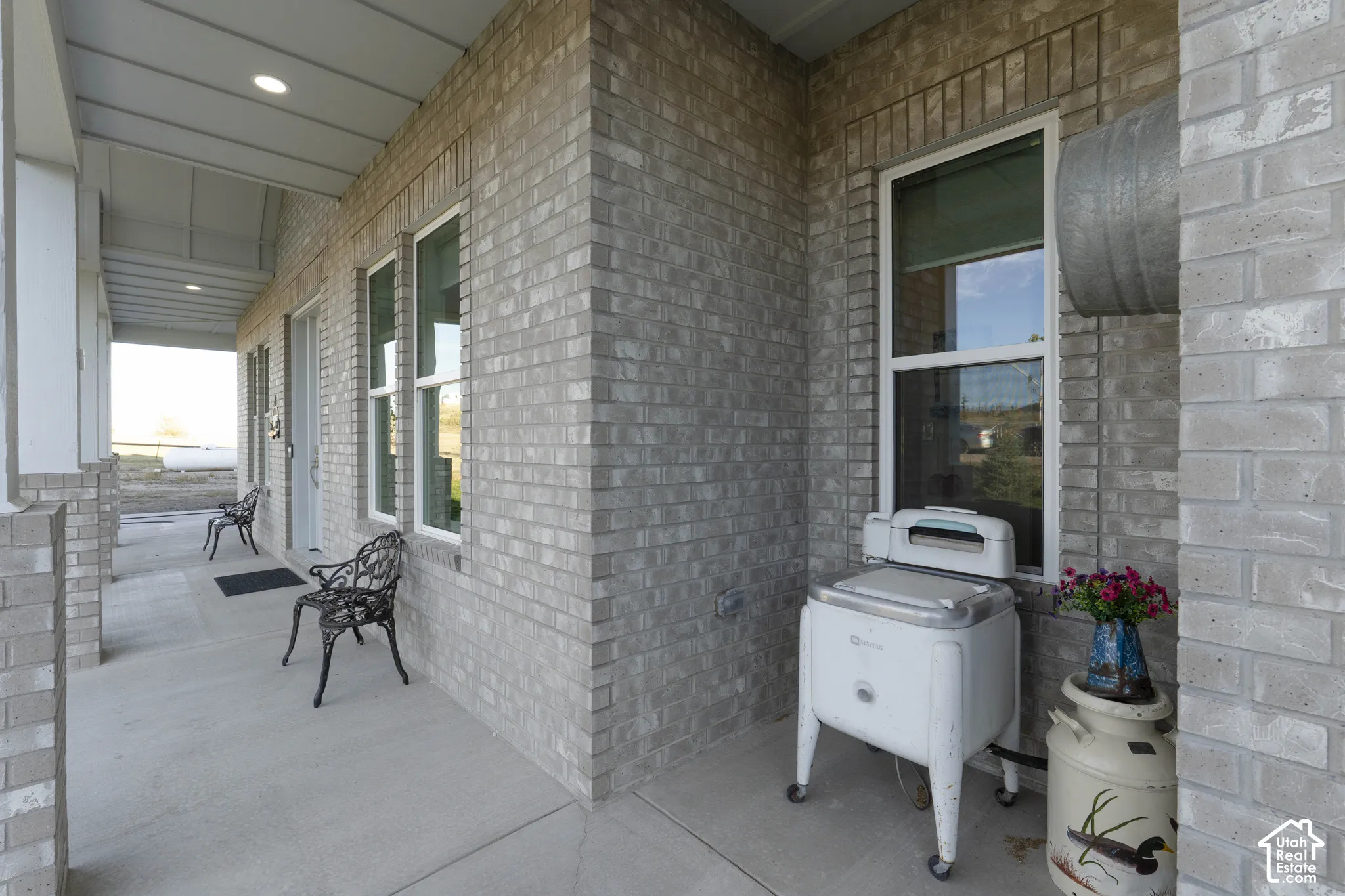 Porch with light-colored brick exterior, white window frames, and recessed lighting
