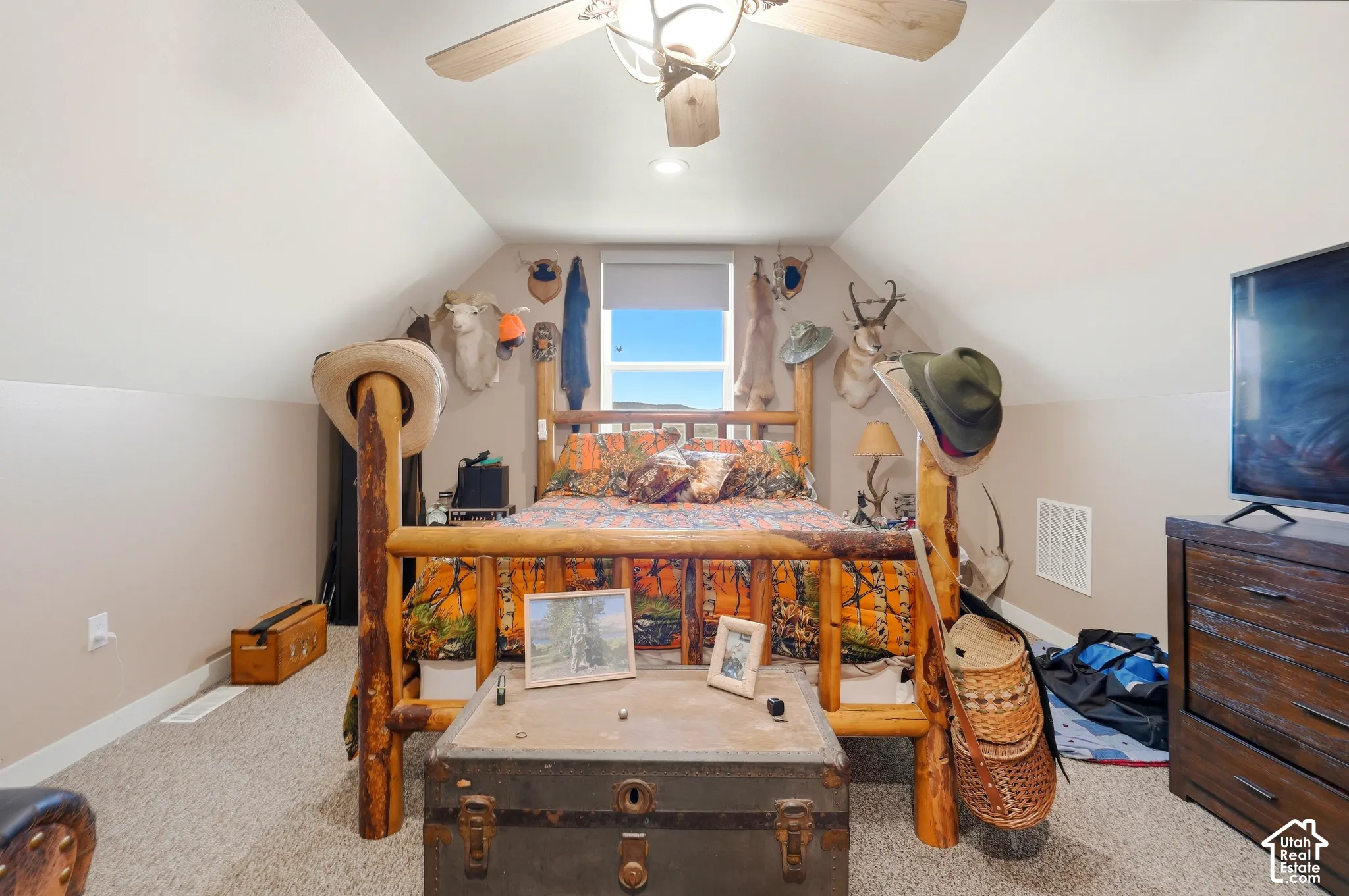 Carpeted room with sloped ceilings, a window, and a ceiling fan with integrated lighting