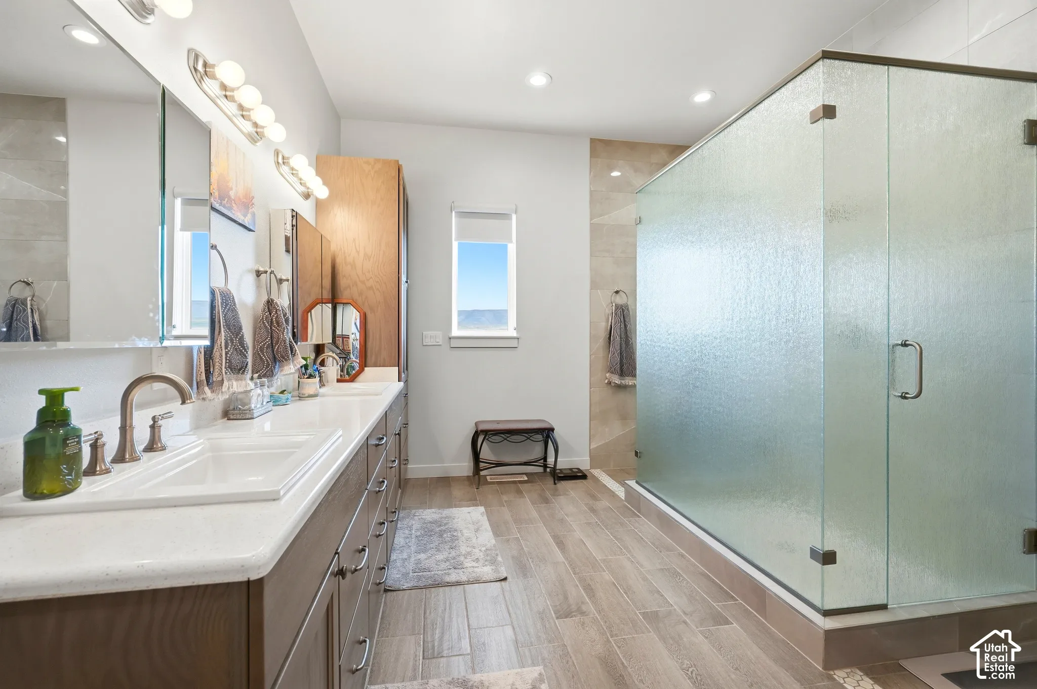 Dual vanity with undermount sinks, wood-finish cabinetry, and solid surface countertops