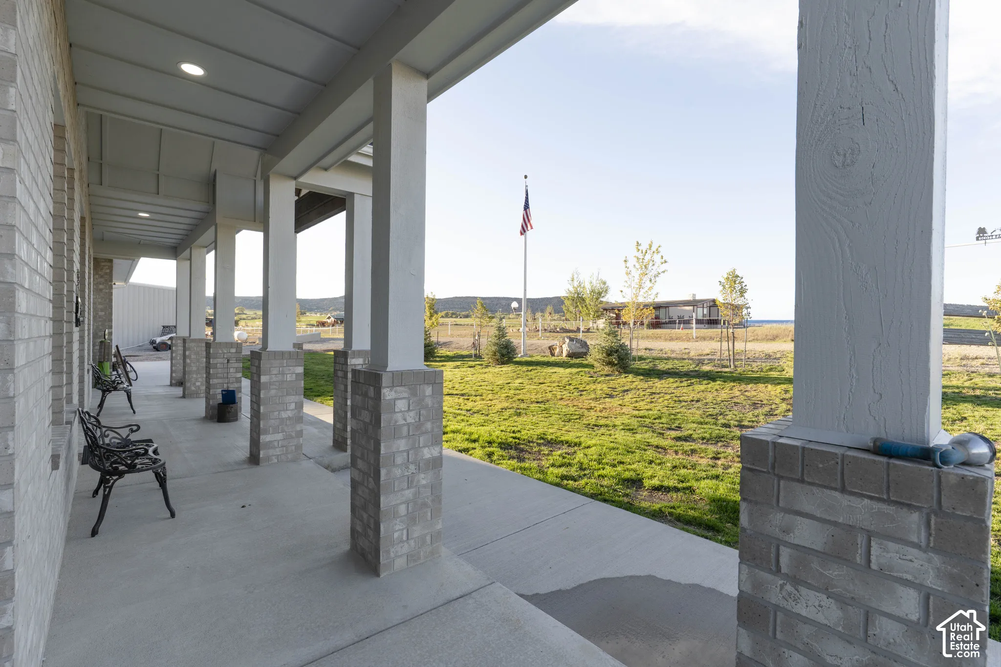 Covered porch featuring brick columns, recessed lighting, and a concrete surface
