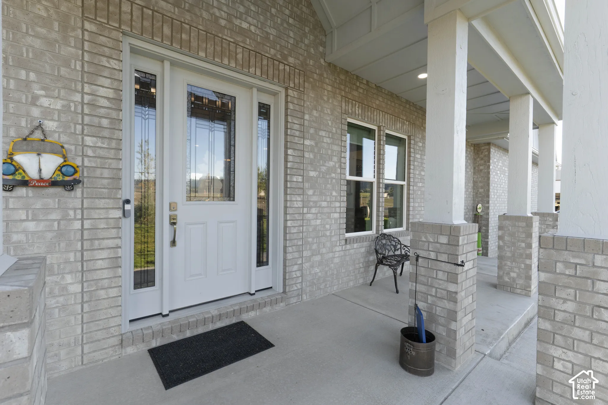 Brick exterior with covered front porch, white columns, and transom window entryway