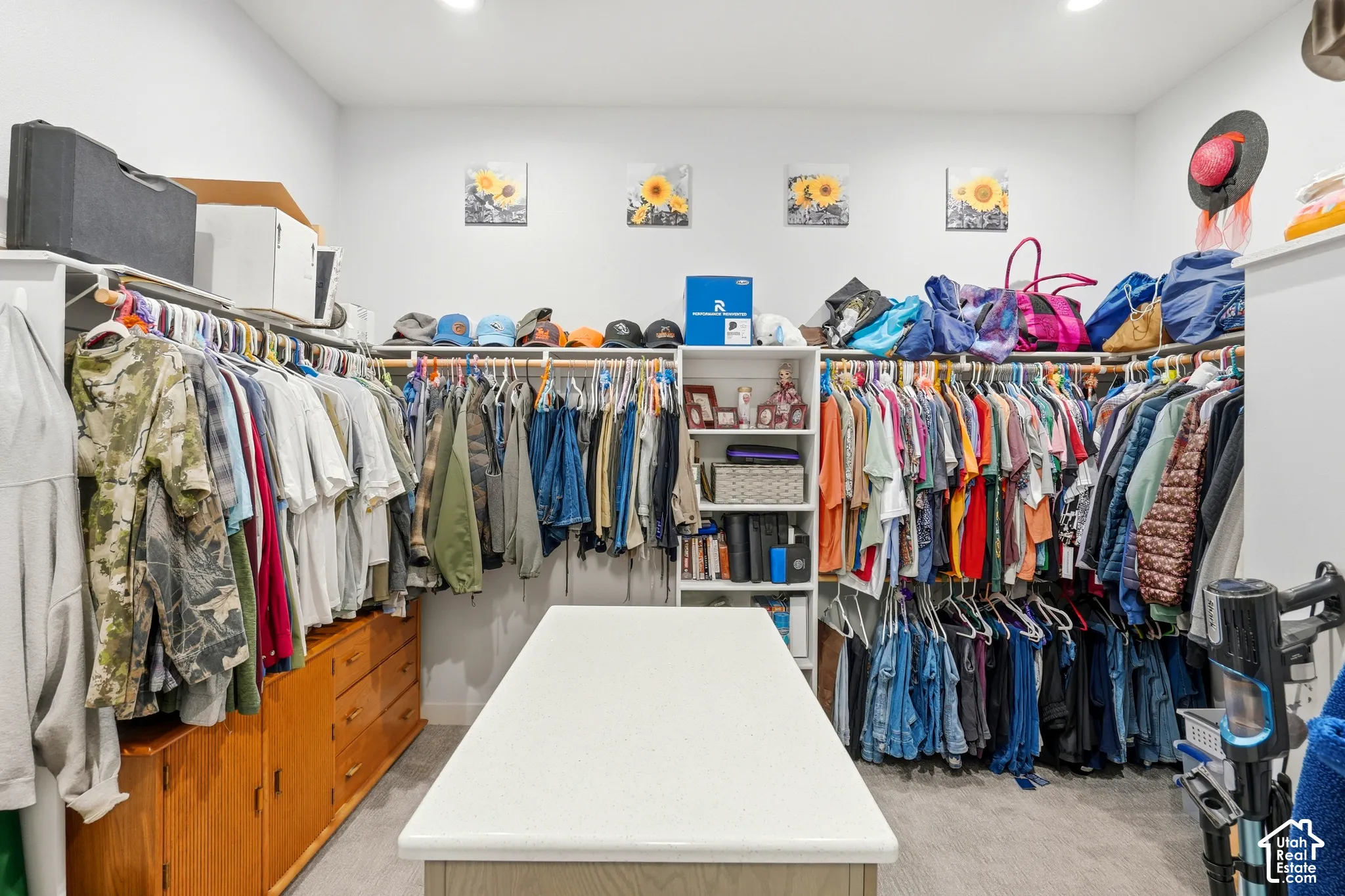 Expansive custom closet featuring extensive hanging storage, multiple shelving units, built-in dresser drawers, and a central island with a white countertop