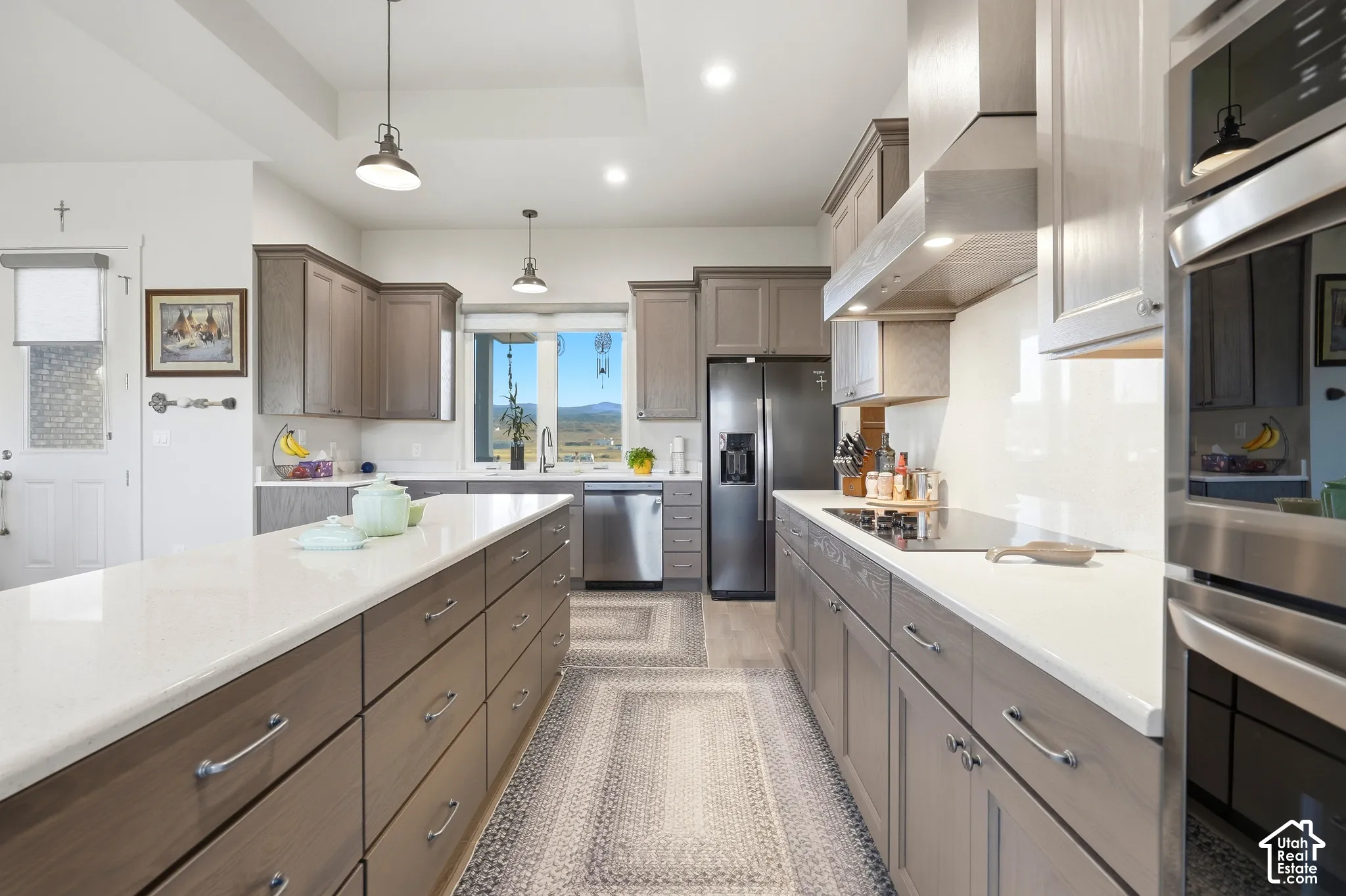 Kitchen featuring a large center island with ample storage, stainless steel appliances, a built-in cooktop, and light wood-finish cabinetry