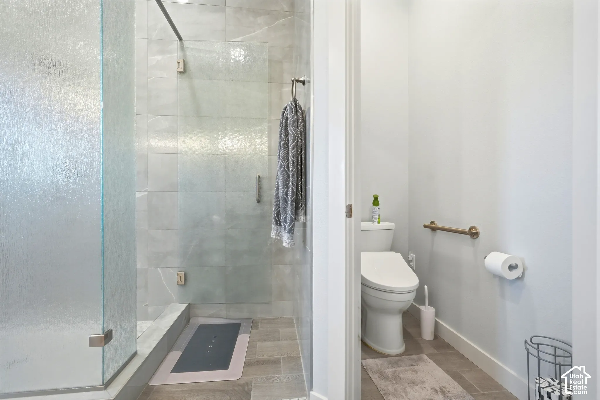 Walk-in shower with clear and textured glass enclosures, light-toned wall tile, and coordinating floor tile