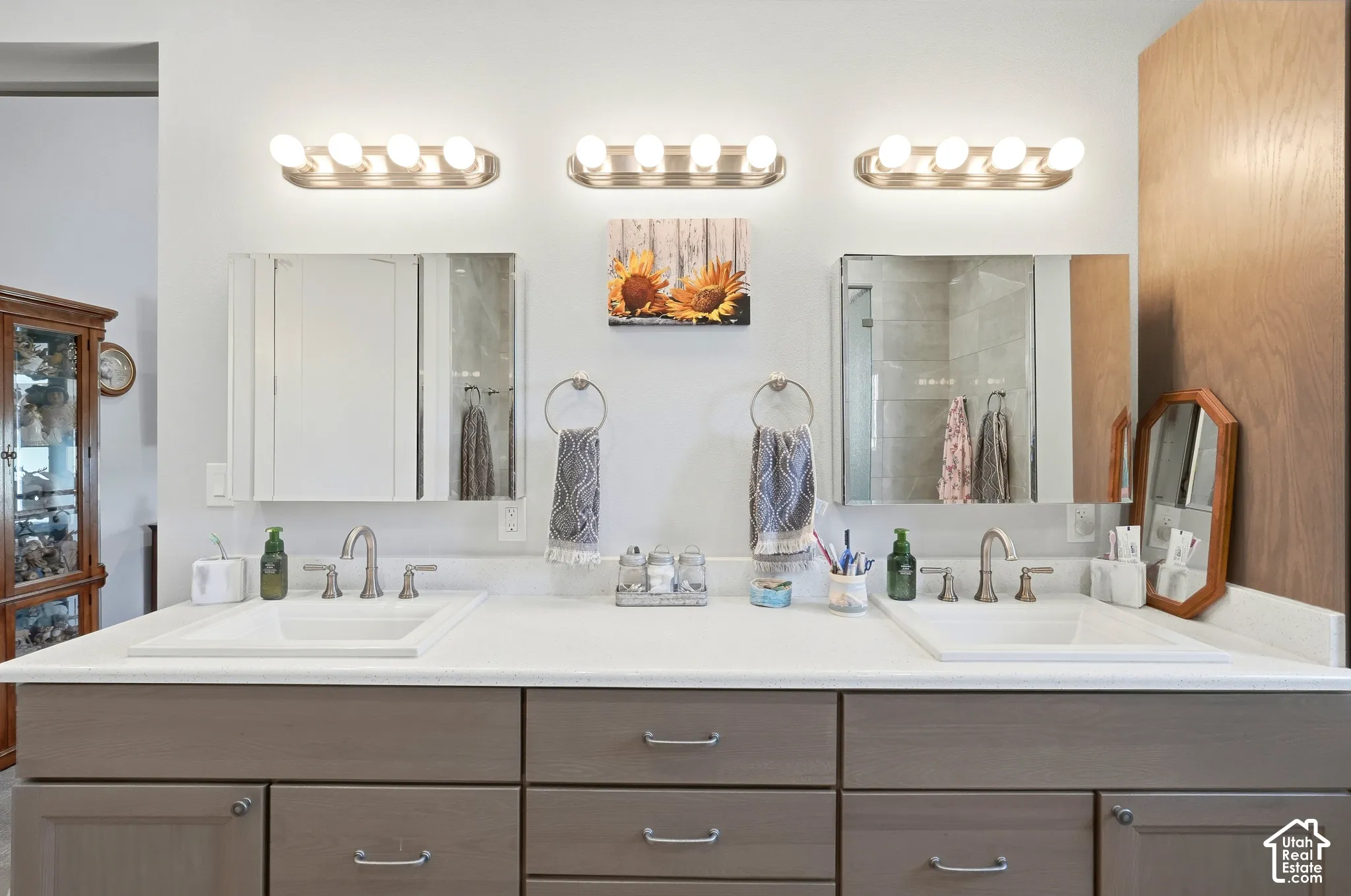 Dual vanity with integrated sinks, brushed nickel fixtures, white countertops, and three wall-mounted light fixtures