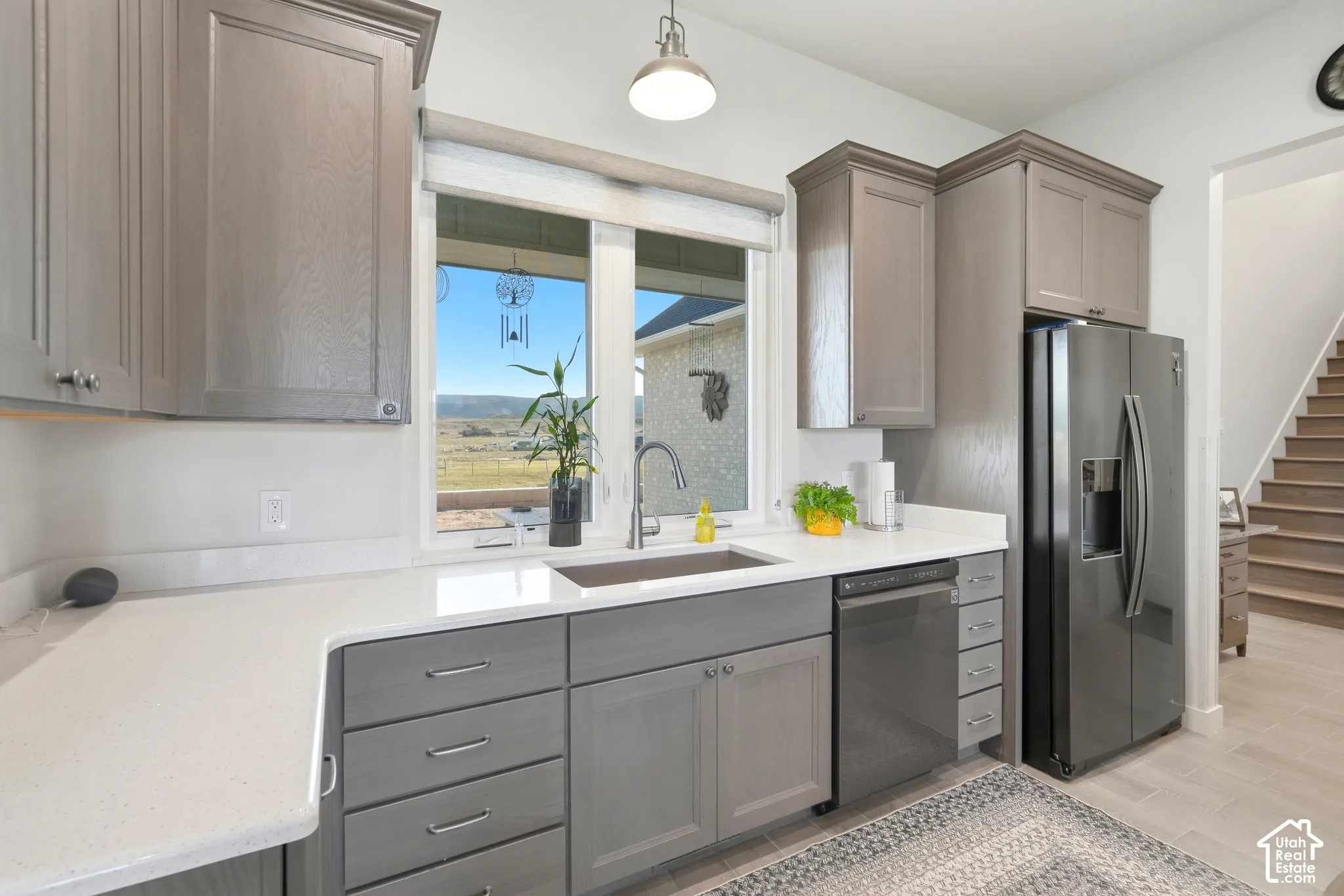 Kitchen featuring gray cabinetry, light countertops, stainless steel appliances, and a window with outdoor scenery