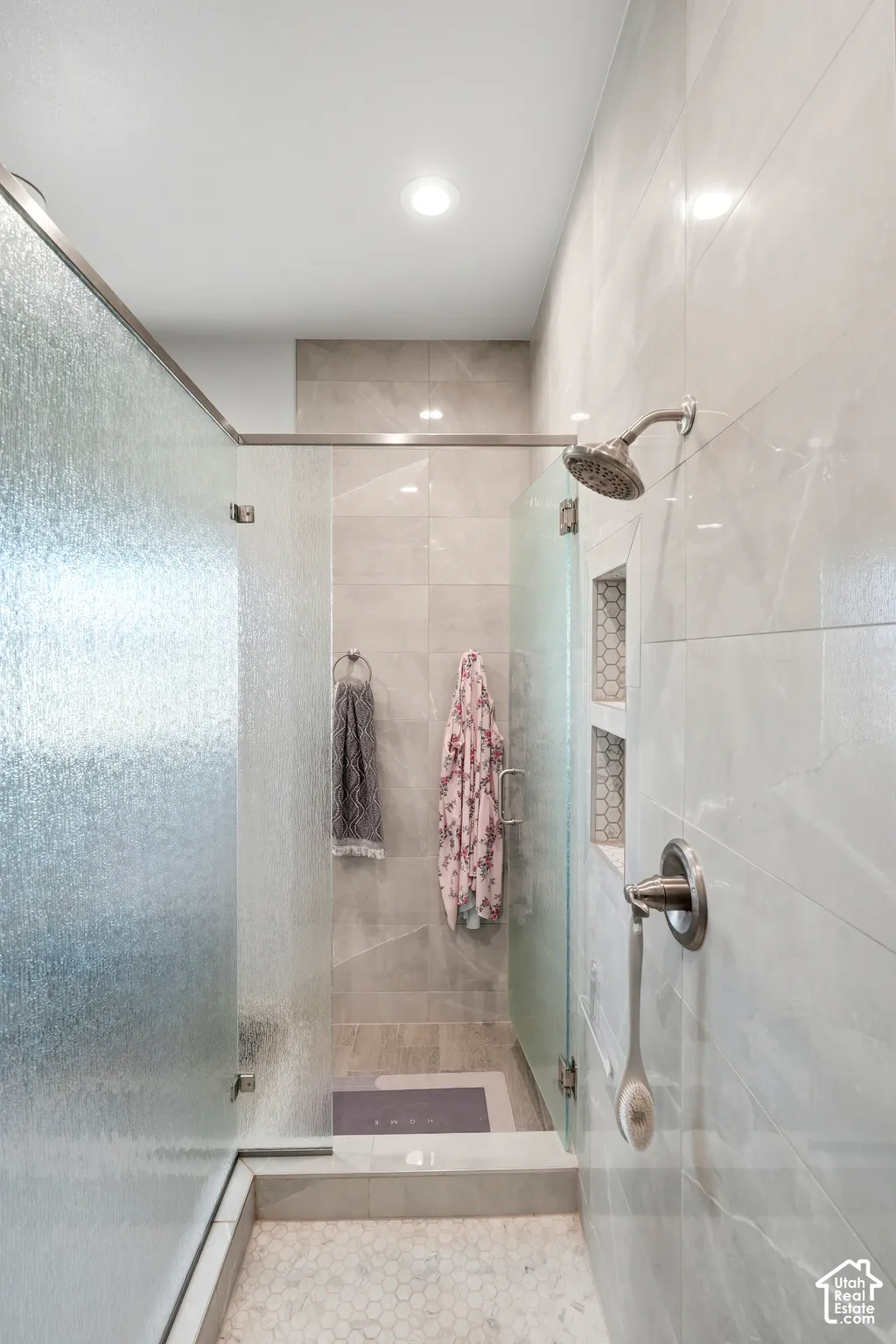 Glass-enclosed shower with a brushed nickel showerhead and control