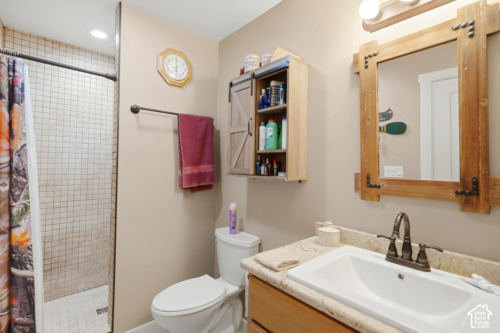 Walk-in shower with tile surround, single vanity with integrated sink, and wood-finish cabinetry
