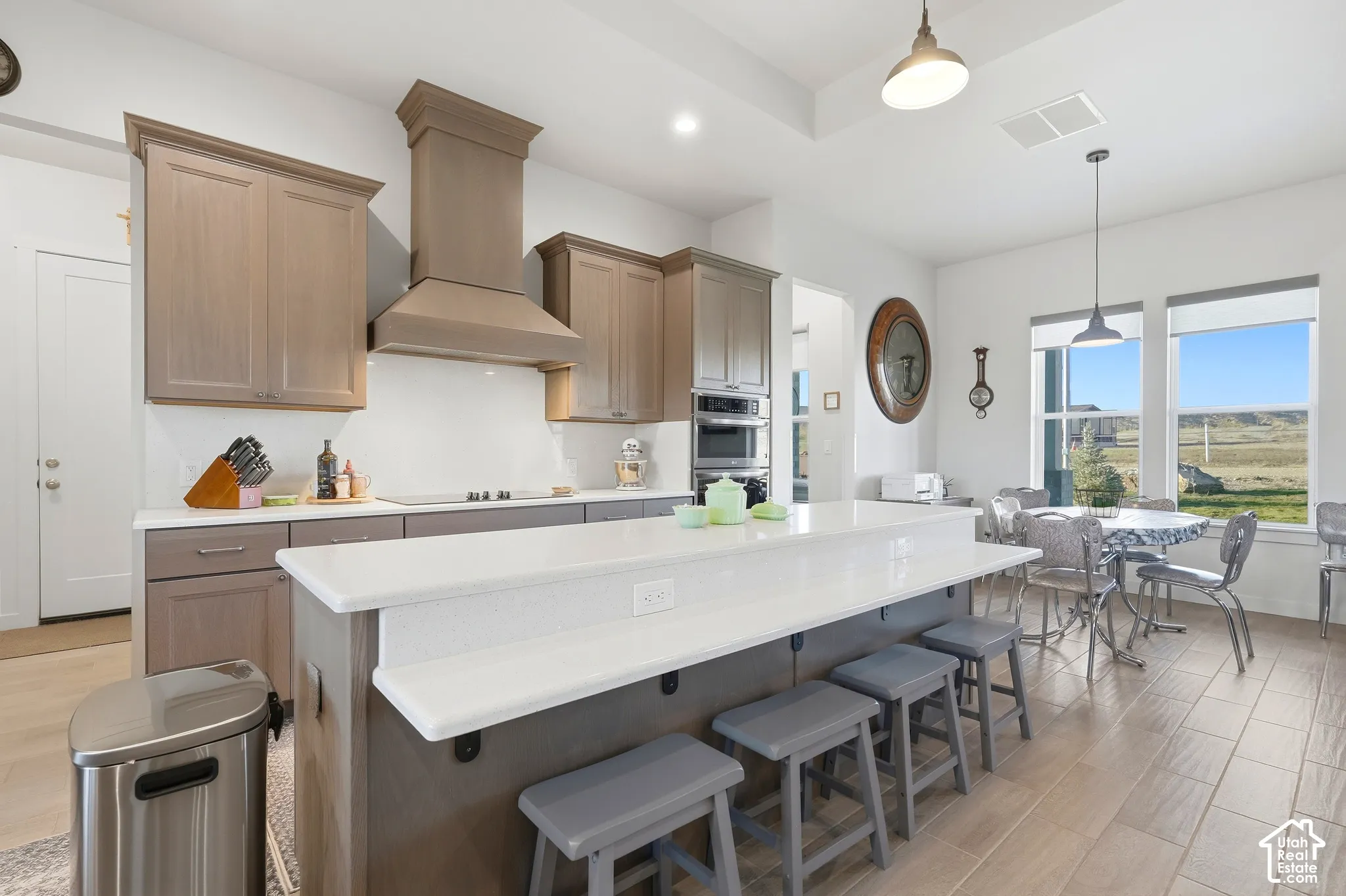 Kitchen featuring a large island with white countertop, recessed lighting, built-in wall oven and microwave, and wood-finish flooring