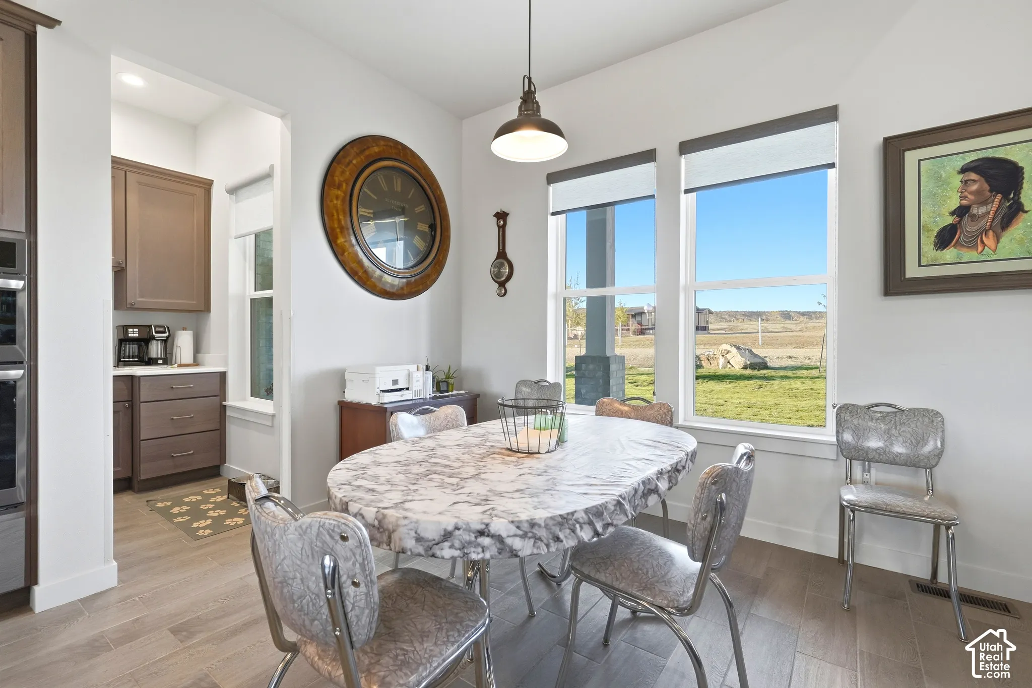 Dining area featuring wood-finish flooring, two large windows with roller shades, and a pendant light fixture