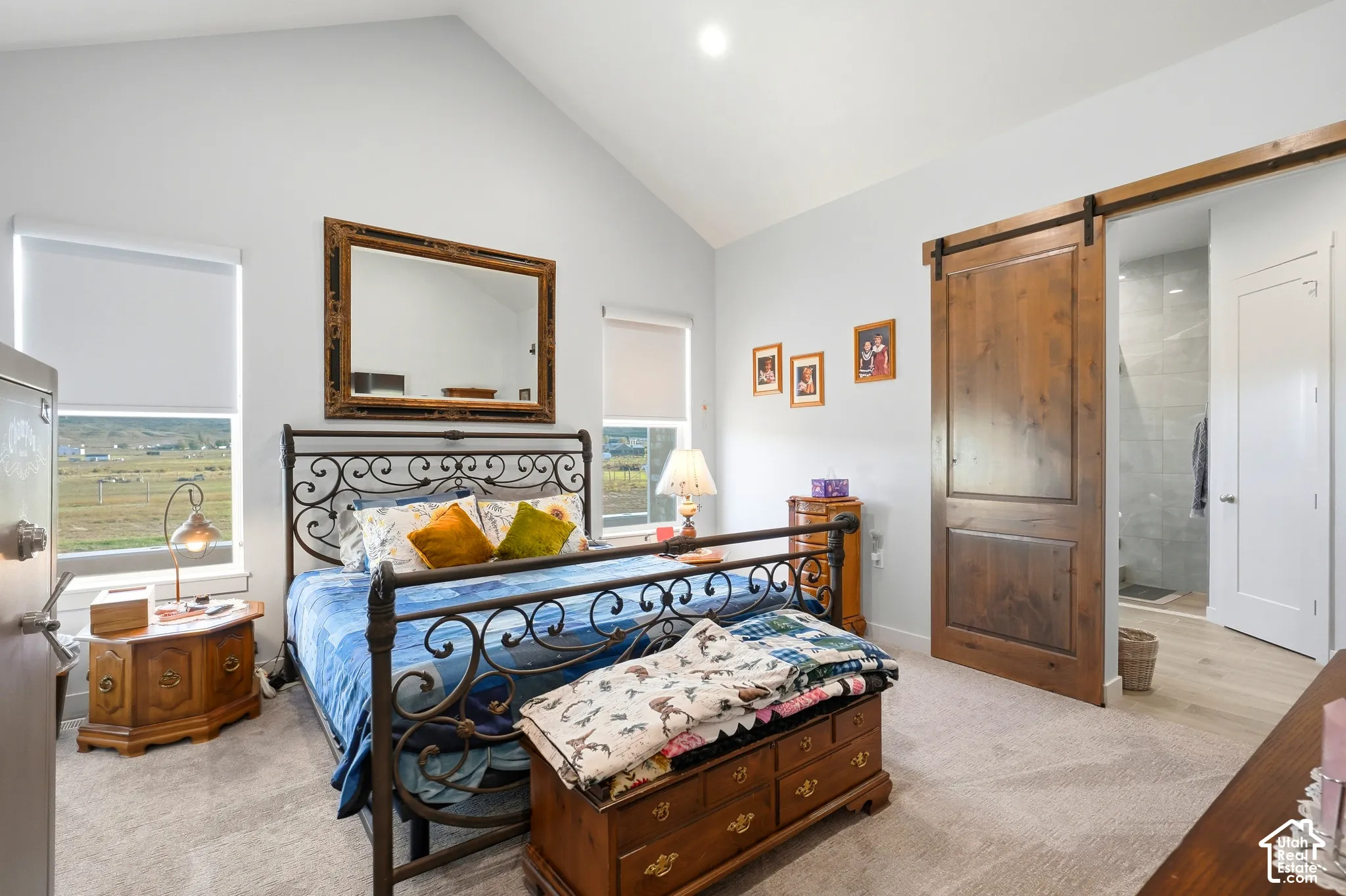 Vaulted ceiling, two large windows, wood-finish barn door, carpeted flooring, and a recessed ceiling light