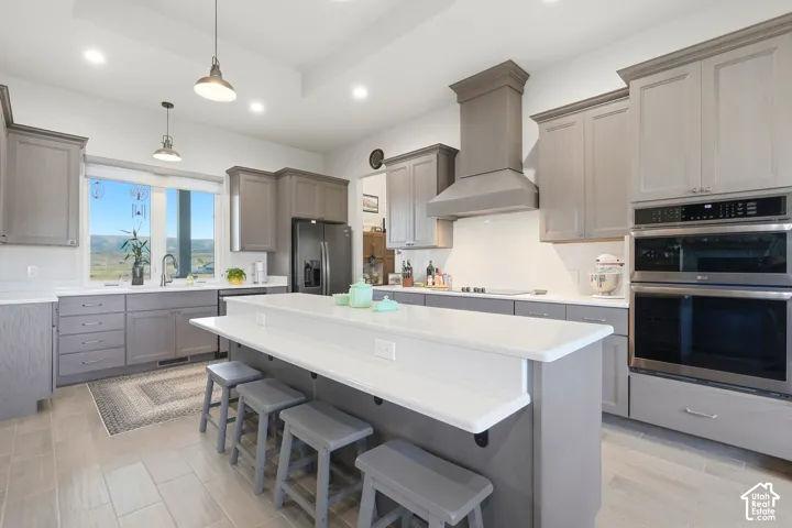 Gourmet kitchen featuring a large central island, light-toned cabinetry, stainless steel appliances, and tile flooring