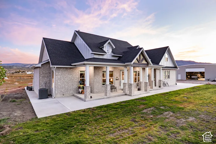 Brick and board-and-batten exterior with a covered front porch featuring stone-clad columns