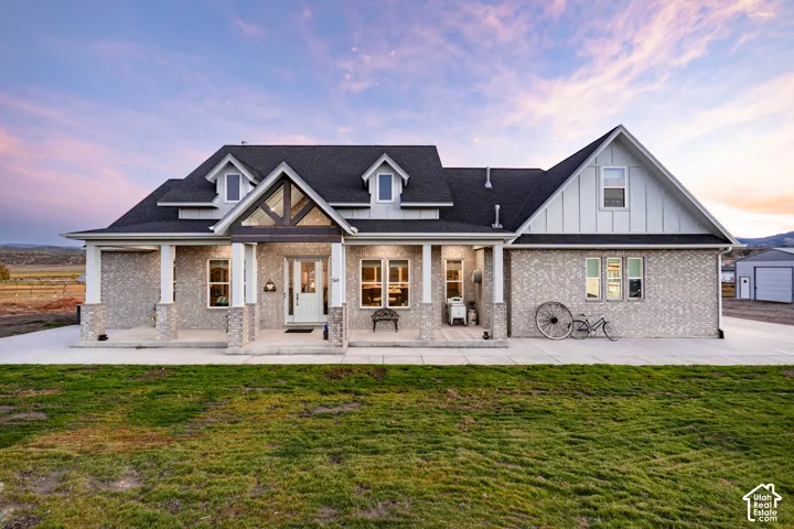 Stone and siding exterior with a covered porch, dormer windows, and a prominent gable entry featuring exposed wood beams