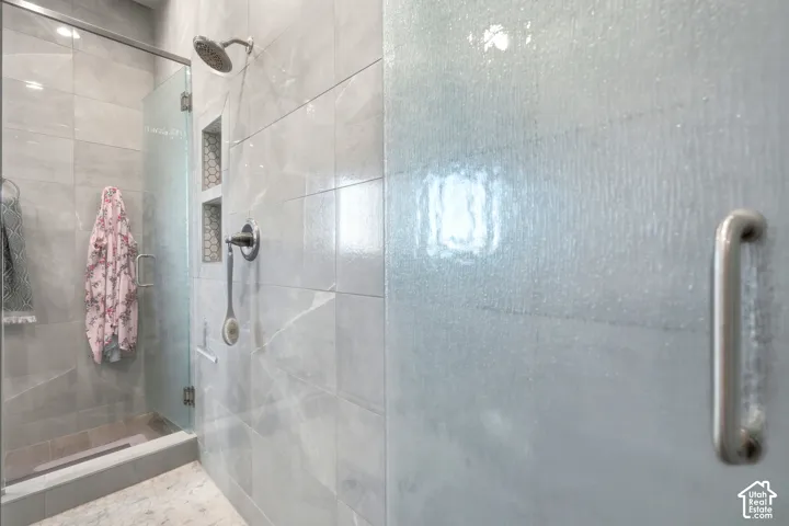 Glass-enclosed shower with gray tiled walls, a built-in hexagonal tile niche, and a rain showerhead