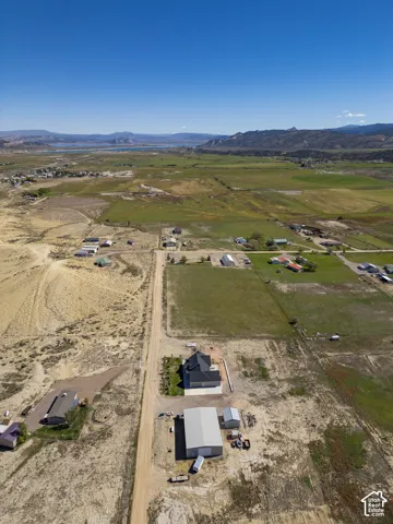 Expansive property featuring a modern residence, large outbuilding, and distant lake and mountain scenery