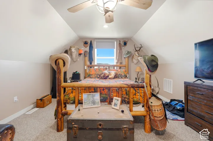 Carpeted room with sloped ceilings, a window, and a ceiling fan with integrated lighting
