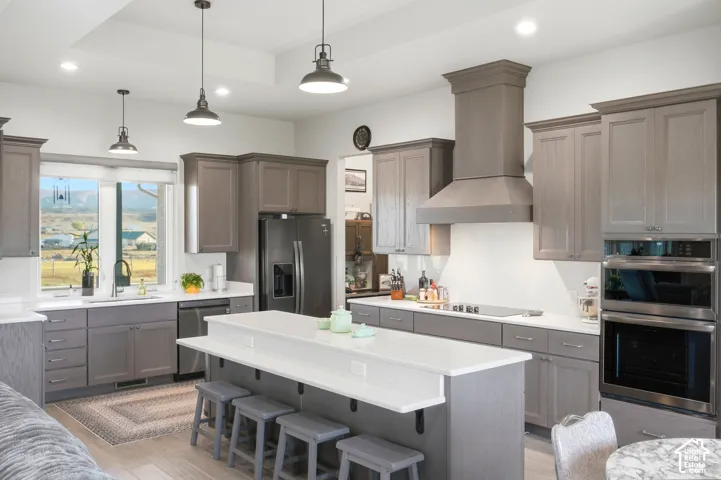 Kitchen featuring gray cabinetry, white countertops, a center island with bar seating, stainless steel appliances, and recessed lighting