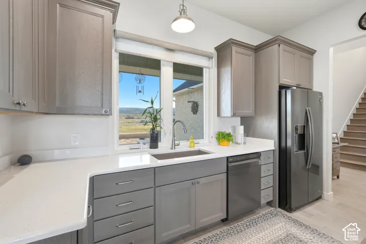 Kitchen featuring gray cabinetry, light countertops, stainless steel appliances, and a window with outdoor scenery