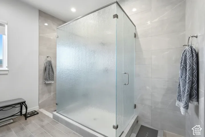Glass-enclosed shower with textured glass panels, tiled shower surround, recessed lighting, and a window with a white frame