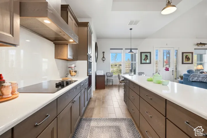 Modern kitchen featuring an extended island with ample storage, light-toned countertops, and wood-finish cabinetry