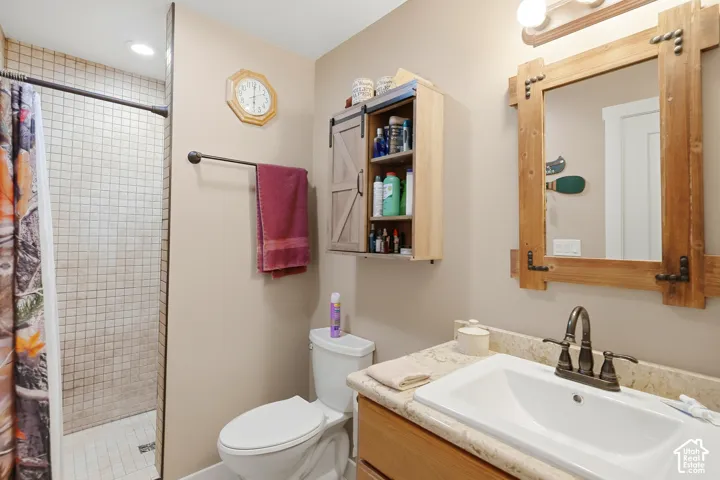 Walk-in shower with tile surround, single vanity with integrated sink, and wood-finish cabinetry