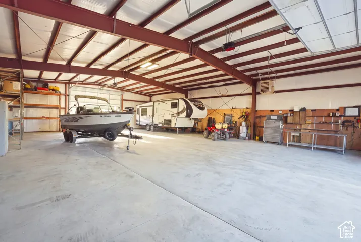Spacious metal structure with a high ceiling, visible steel beam construction, overhead lighting, and a concrete floor