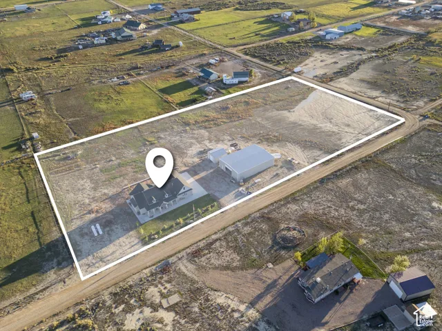 Spacious lot featuring a large single-story residence, separate expansive outbuilding, and a gravel driveway