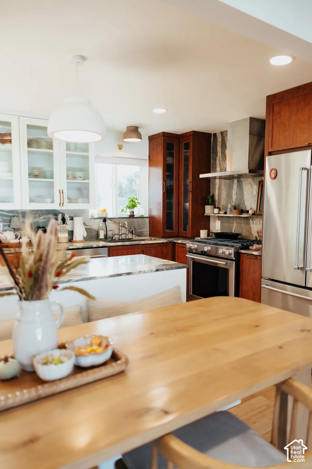 Kitchen featuring a central island with stone countertop, two-toned cabinetry, stainless steel range with overhead hood, and recessed lighting